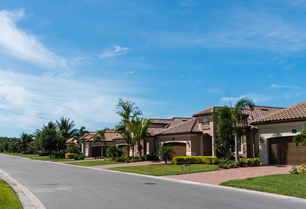 Street-level view of a mid-rise apartment complex with palm trees and clean urban landscaping, representing managed multifamily housing.