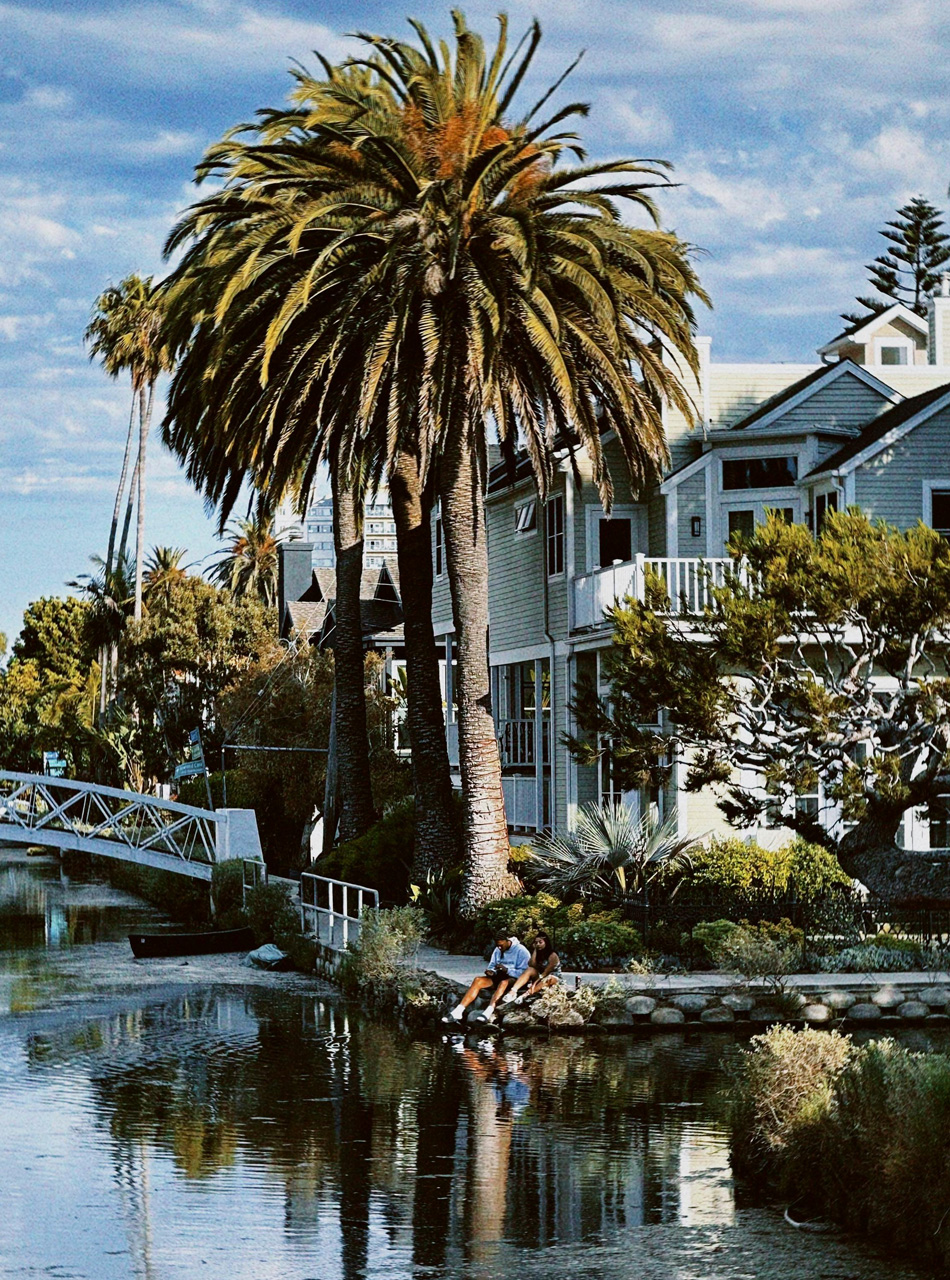 Modern single-family homes with balconies and palm trees under a clear blue sky, representing land development in Southern California.