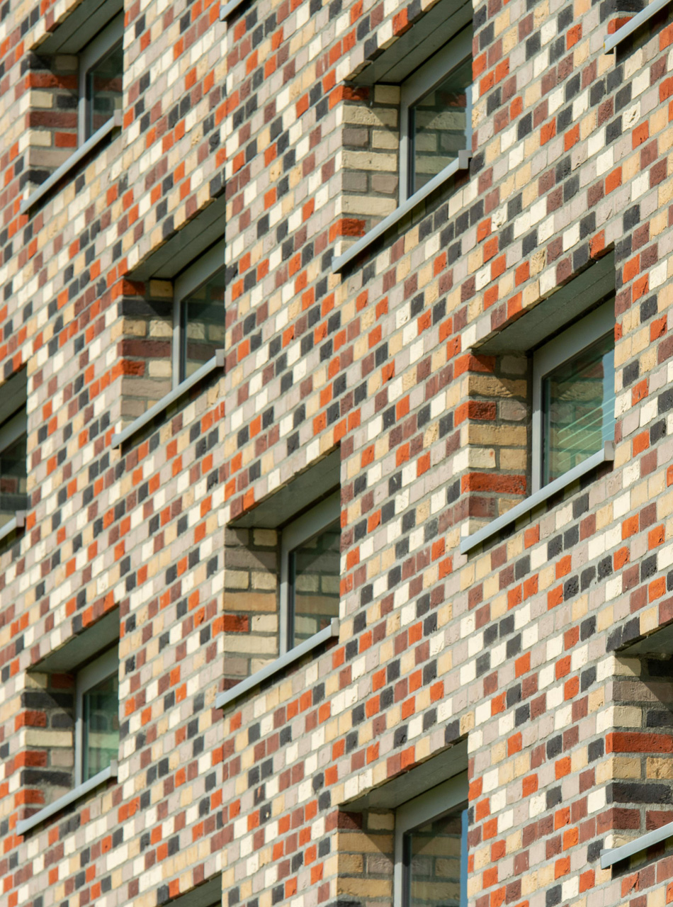 Close-up of a colorful student housing building facade with a geometric brick pattern.